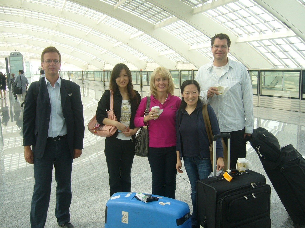 Fünf Personen stehen mit ihren Koffern an einem Flughafen 